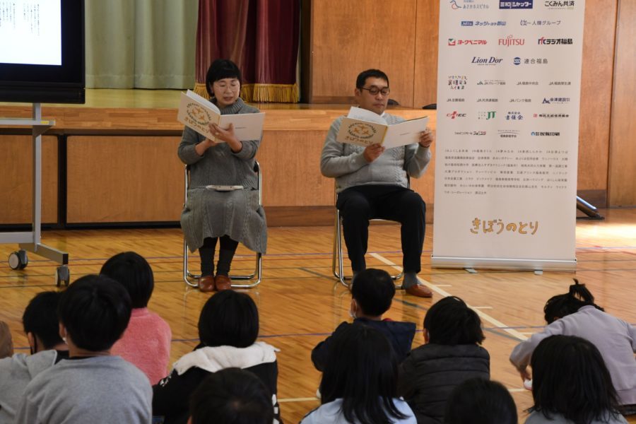 江藤さん（右）とよしもとさんの読み聞かせに耳を傾ける谷田川小の児童